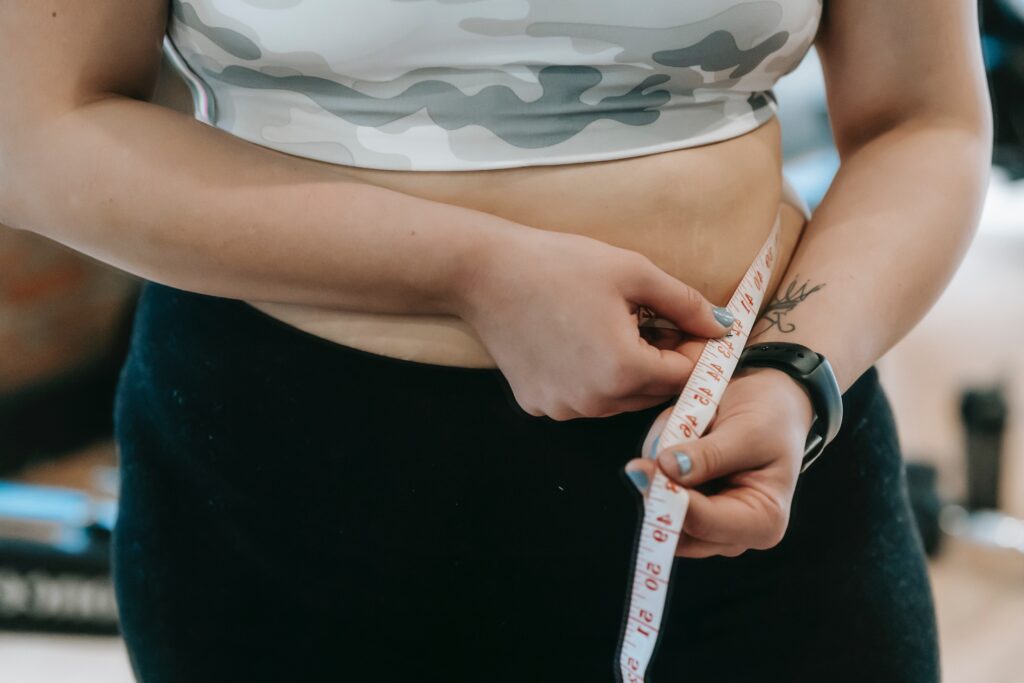 woman with measuring tape around stomach to track weight loss