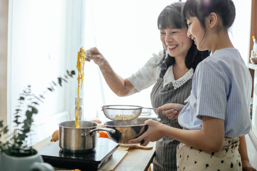 mother and daughter eating healthy together cooking in kitchen